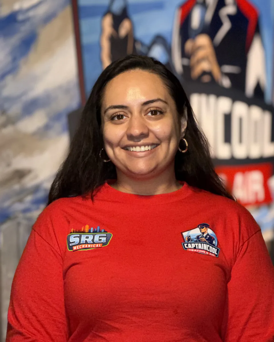 Smiling Captain Cool Heating & Air team member in a red company shirt in front of the captain mural